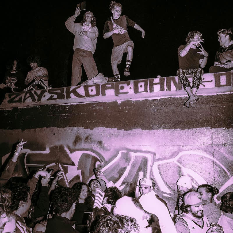 Ravers standing on a graffiti wall above the crowd, flash photography